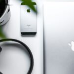 elettronica green space gray iPhone SE beside headphones and silver MacBook