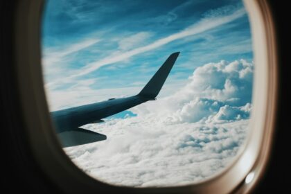 person taking picture of plane wings while flying during daytime