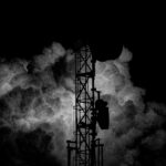 a black and white photo of a tower in the clouds