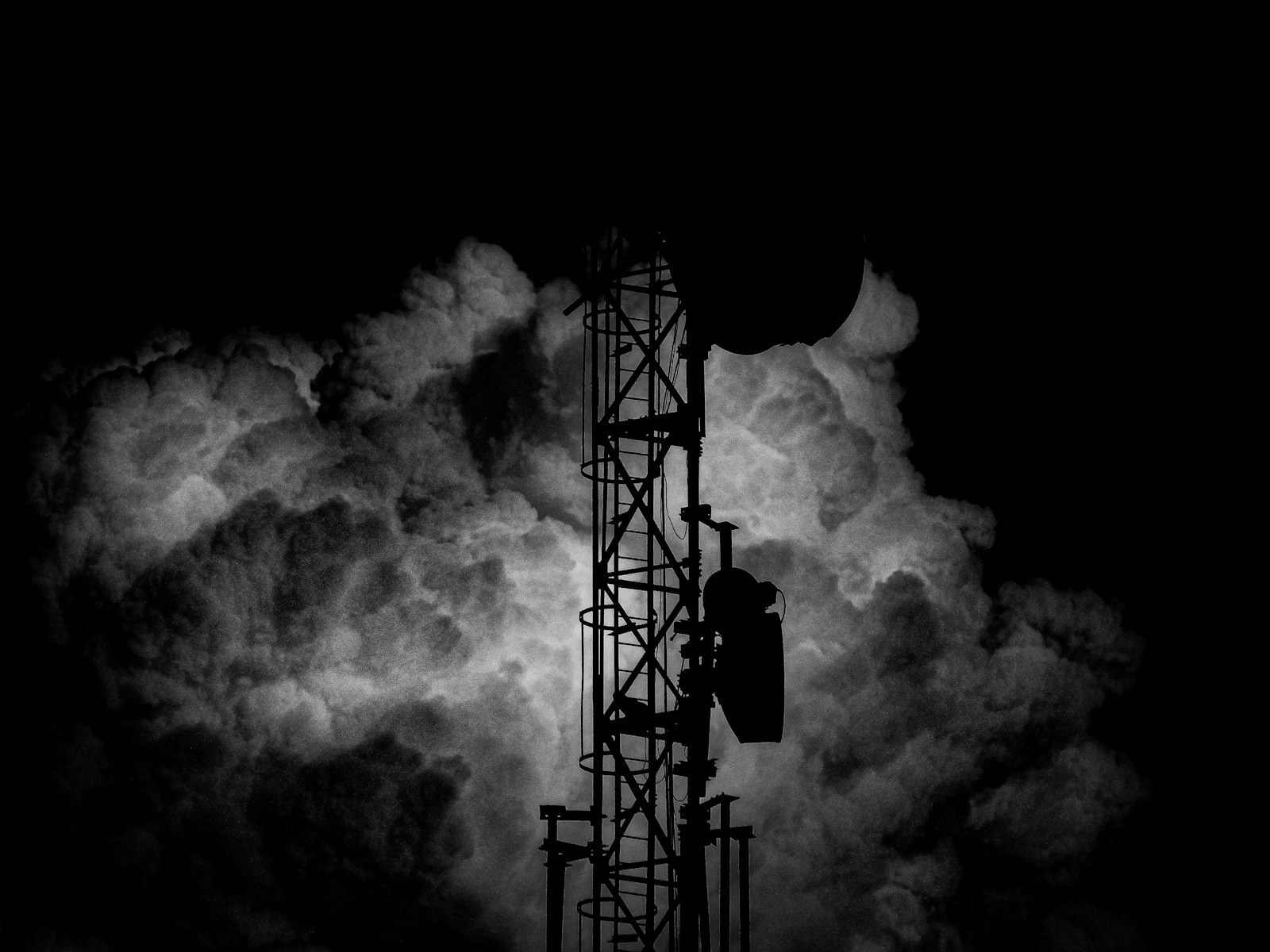 a black and white photo of a tower in the clouds